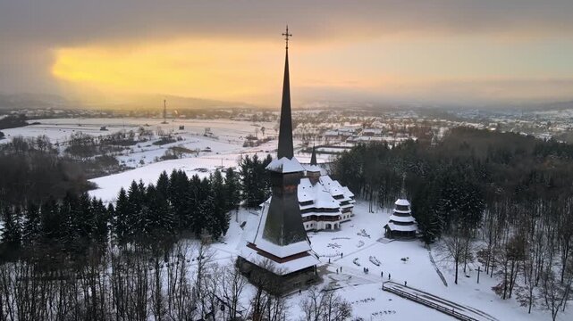 Aerial view of wooden monastery Sapanta Peri in Maramures Romania during winter sunset with snow covered landscape