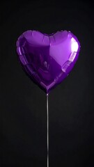Shiny purple heart-shaped balloon tethered with string against a dark, soft background