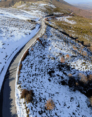 Aerial View of a Winding Mountain Road Surrounded by Snow
