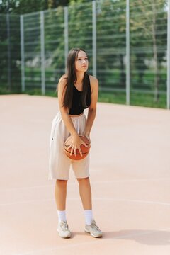 Woman Holding Basketball On Outdoor Court going to is about to throw in the basket.