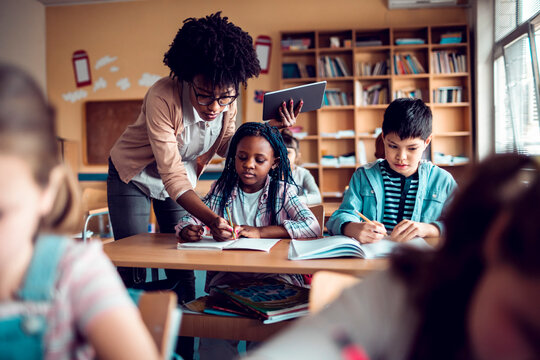 Teacher helping students during lesson in elementary classroom