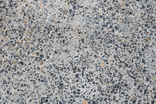 A detailed view of an exposed aggregate concrete floor, showcasing a rich variety of natural stones and pebbles.
