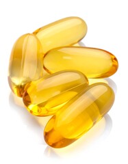 Shiny, translucent, golden-yellow capsules piled on a white reflective surface. Studio shot