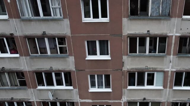 The exterior of a multi-storey apartment building with dirty balconies and windows. An urban landscape in a depressed, poor neighborhood. The urban ghetto.