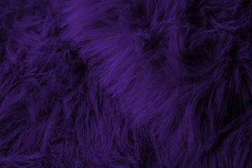 Vibrant dark purple shaggy faux fur plush fabric creating a luxurious soft textile background pattern
