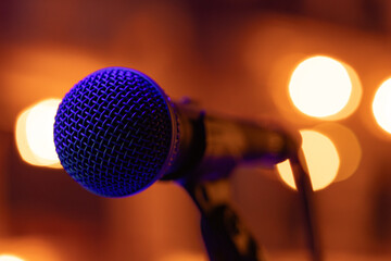 Obraz premium Professional Vocal Microphone with Blue Lighting on Warm Golden Bokeh Background