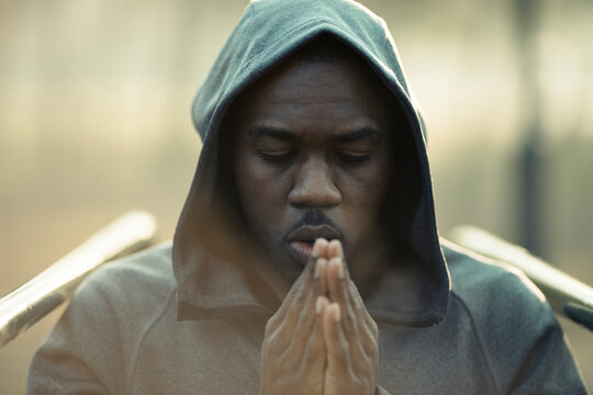 Man in hoodie praying outdoors