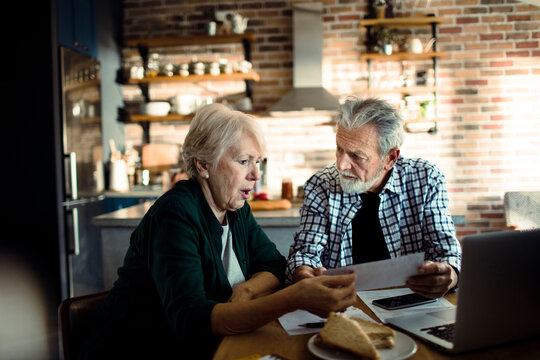 Senior couple reviewing bills at home kitchen