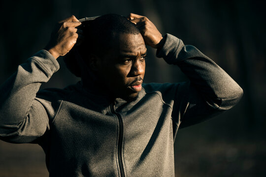 Focused athlete pulling up hoodie outdoors
