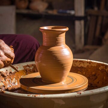 A skilled ceramic artist uses wet clay and a pottery wheel to craft a handmade earthenware vase with expert fingers
