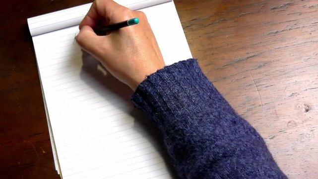 Close view of a hand writing the words &ldquo;My Tablet&rdquo; on a notebook placed on a wooden table, conceptual scene about digital life and technology, minimal composition with empty space on the right