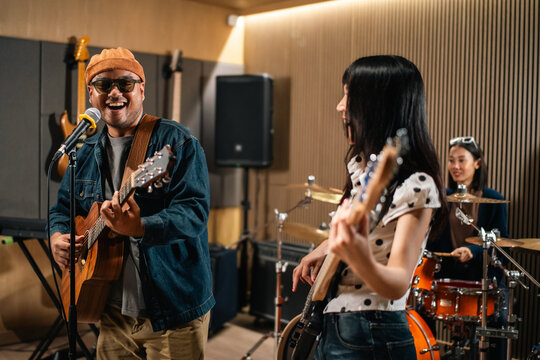 Young asian music group Band members rehearse with instruments guitar bass drum. Teamwork music band practice in studio prepire perform. Vocalist and band