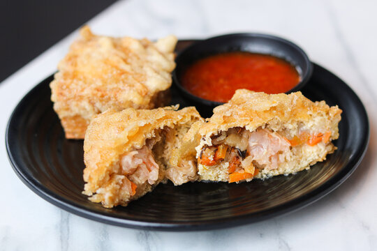 Closeup plate of crispy stuffed tofu, also known as tahu kipas in Indonesia. A snack or appetizer consisting of deep-fried firm tofu pockets that are stuffed with vegetables and shrimp.