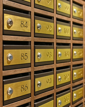 Vintage brass postal mailboxes in a wooden wall