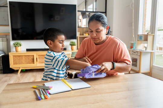 Mother helping son with schoolwork at home