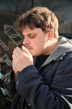 Young man lighting cigarette outdoors in profile