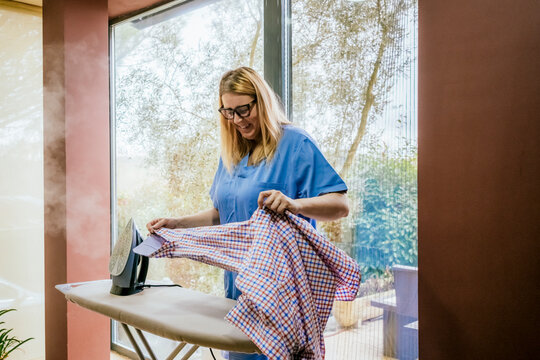 Woman enjoying ironing near a window