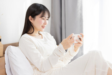 寝起きでスマホ使う女性