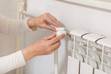 Closeup of a radiator thermostat with man waker hand.