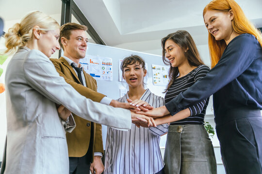 Business team showing unity success with hands together in office, teamwork collaboration and power motivation, diverse colleagues celebrating achievement corporate goal partnership