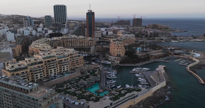 Aerial view of Spinola Bay's harbor and Portomaso's tall buildings, with a striking contrast between the city's architecture and the blue sea, St. Julian's, Malta.