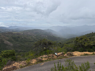 High-angle view of a vast mountain valley under a cloudy, melancholic sky with a winding road