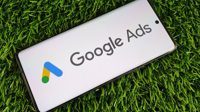 Google Ads logo on smartphone screen on green grass background