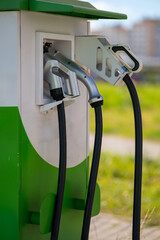 Close-up of an electric vehicle charging station with two charging connectors and cables.
