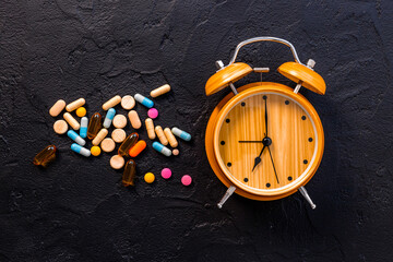 Medical treatment pills and vintage alarm clock, top view. Time to take medicine concept