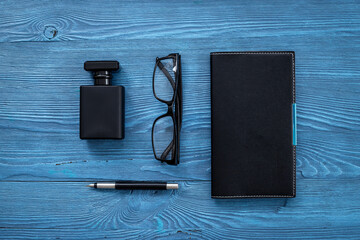 Male accessories flat lay with perfume notepad and glasses in black color
