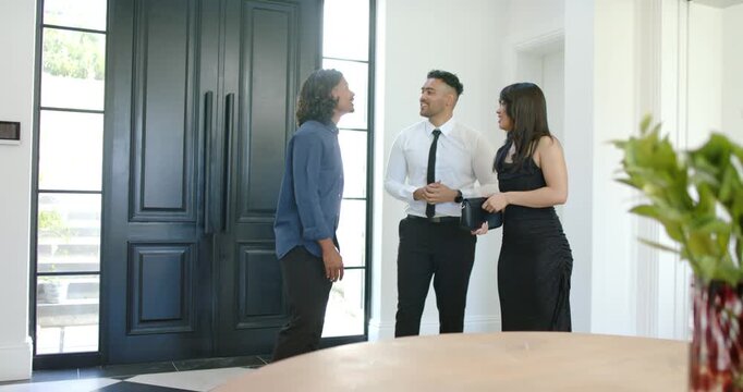 African American couple meeting host formally at entry, left man speaking gesturing by black doors
