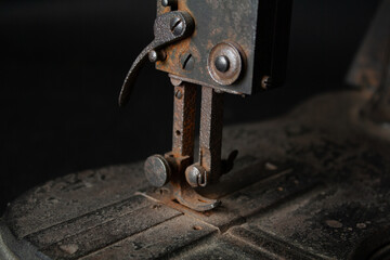 Close-up view of a very old, rusty sewing machine and its parts, showing corroded metal surfaces, worn mechanisms, and timeworn details. 
