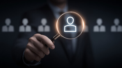 Magnifying glass selecting a user icon representing recruitment and candidate search.
