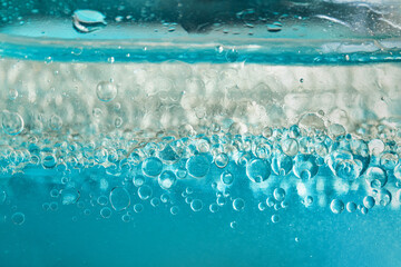 Blue and white two-phase skincare serum creating an abstract background texture with numerous bubbles