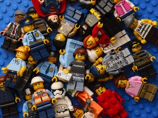 Fototapeta premium Tambov, Russian Federation - February 02, 2026 Pile of Lego minifigures on blue baseplate background