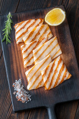 Grilled squid steaks with rosemary and lemon on dark wooden cutting board