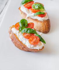 Gourmet bruschetta with stracciatella cherry tomatoes basil and balsamic on bright rustic background