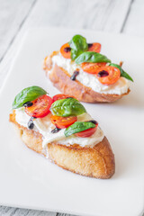 Gourmet bruschetta with stracciatella cherry tomatoes basil and balsamic on bright rustic background