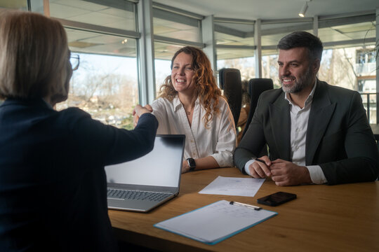 Smiling lawyer, realtor or financial advisor handshaking young couple thanking for advice, insurance broker or bank worker and millennial customers shake hands making deal, investment or taking loan