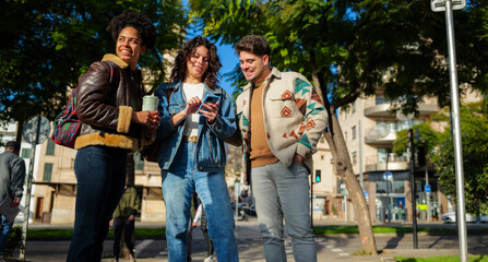Diverse group of young adult friends enjoying a sunny day in an urban setting, gathering around a smartphone screen and sharing cheerful moments, expressing connection and technology use