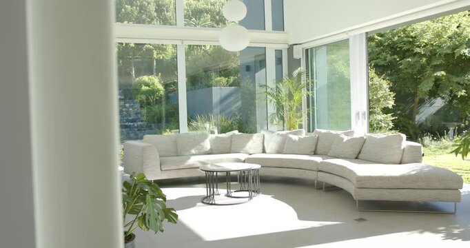 Camera starting blocked by column, moving right and revealing curved gray sofa, tables and garden