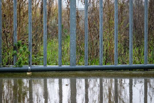 Rain-reflecting metal bars with industrial harbour backdrop