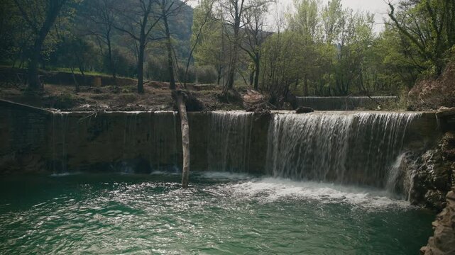 A waterfall flowing into a pond in the forest. Assisi, Italy.