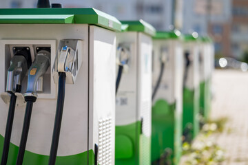 Row of electric vehicle charging stations with plugged-in connector and cable.