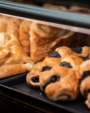 View of golden pastries and dark poppy seed rolls gleaming under the warm lights of a bakery display case, Hallstatt, Upper Austria, Austria.