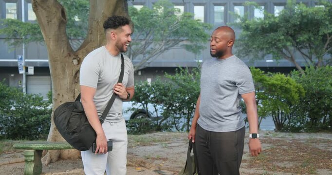 Two adult male friends meeting in park, right man checking watch starting brief fist bump greeting