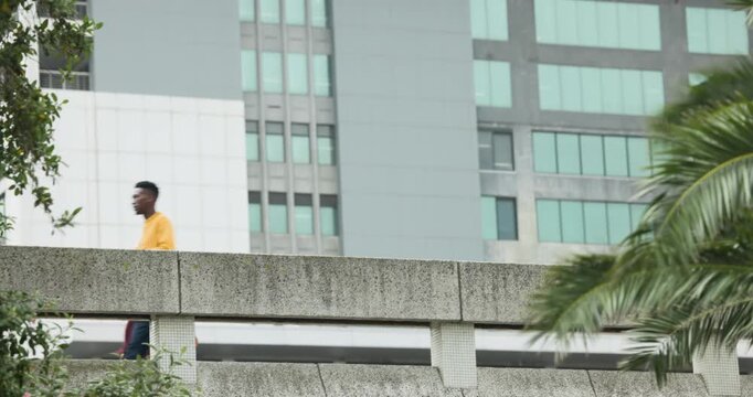 Man in yellow sweater entering from right, walking across parapet commuting, woman using smartphone