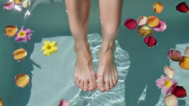 Feet submerged in water with floating flower petals and leaves Keywords: feet, submerged, water