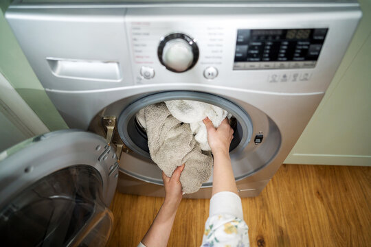 Washing machine at home. Smart appliances. Woman loading the washing machine with towels. Daily chores. Cleaning laundry