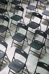 Rows of empty black folding chairs in a bright room